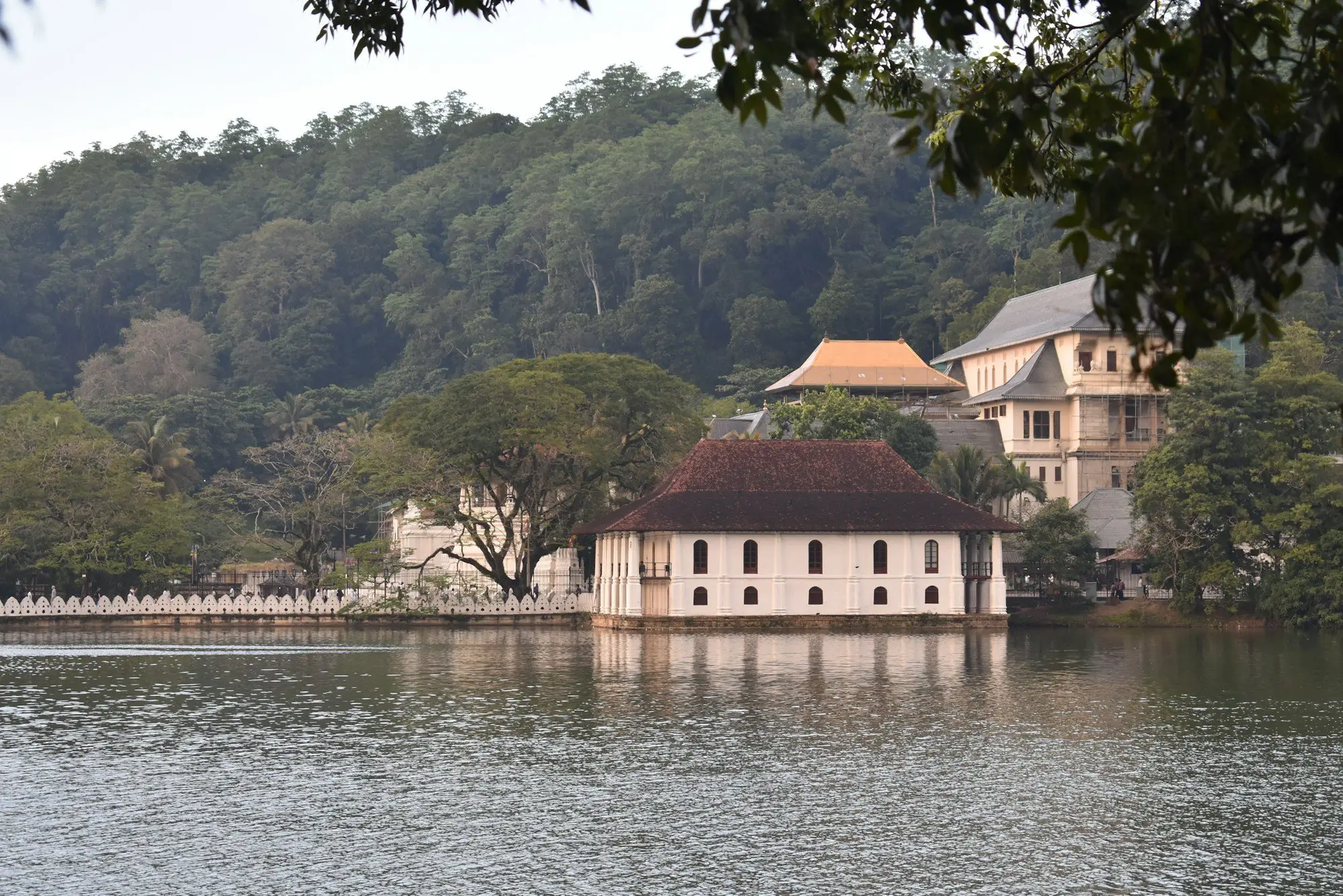 Kandy Lake with temple buildings and forested hills